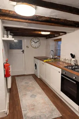 a kitchen with a sink and a clock on the wall at Cosy Town centre Historic Tudor Cottage & parking sleeps 6 in Shrewsbury
