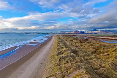 a sandy beach with the ocean and mountains in the background at Finest Retreats - Bryn Awelon in Harlech