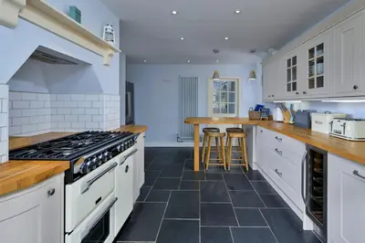 a kitchen with white cabinets and black tile floors at Finest Retreats - Bryn Awelon in Harlech