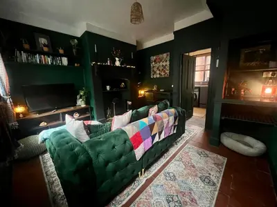 a living room with a green couch and a television at Cosy, quirky Victorian house on Waterfall Street in Llanrhaeadr-ym-Mochnant