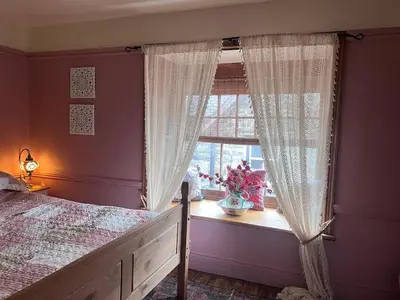 a bedroom with a bed and a window with curtains at Cosy, quirky Victorian house on Waterfall Street in Llanrhaeadr-ym-Mochnant