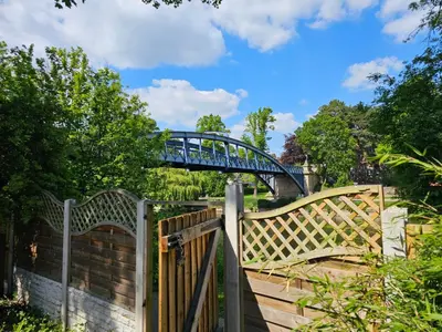 a blue bridge over a canal with a wooden fence at Ever popular 2 bedroom riverside home - to sleep 4 - Pass the Keys in Shrewsbury