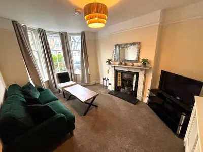 a living room with a green couch and a fireplace at Victorian House in Cherry Orchard, Close to Town in Shrewsbury