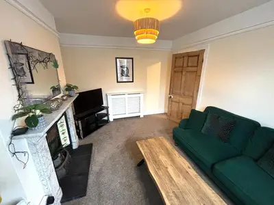 a living room with a green couch and a fireplace at Victorian House in Cherry Orchard, Close to Town in Shrewsbury