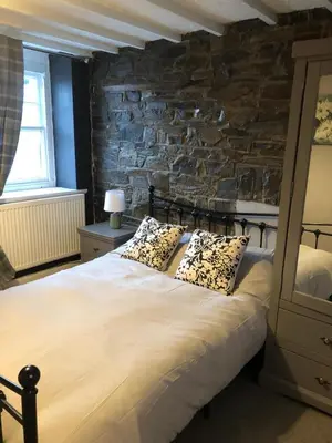 a bedroom with a large bed with a stone wall at Cosy Pubs Bed & Breakfast in Rhayader
