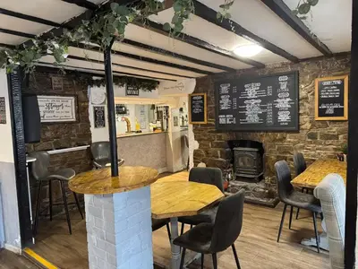 a restaurant with tables and chairs and a brick wall at Cosy Pubs Bed & Breakfast in Rhayader