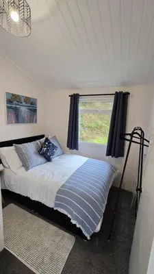 a bedroom with a large bed with a window at Welsh Coast Seaview 2 Bedroom Wooden Lodge at Clarach Bay in Aberystwyth