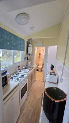 a kitchen with a stove and a sink in it at Welsh Coast Seaview 2 Bedroom Wooden Lodge at Clarach Bay in Aberystwyth