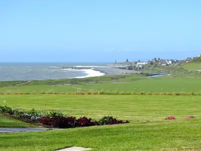 a green field with the ocean in the background at Sea View in Rhyd-y-felin