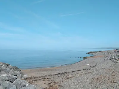 a rocky beach with a row of posts in the water at Sea View in Rhyd-y-felin
