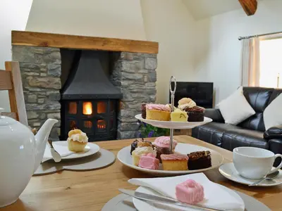 a table with three plates of cupcakes and a fireplace at Awel Y Mynydd - Mountain Breeze in Strata Florida