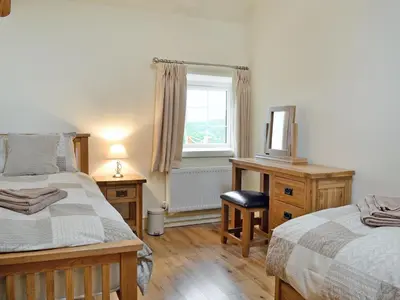 a bedroom with two beds and a desk and a window at Awel Y Mynydd - Mountain Breeze in Strata Florida