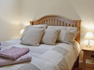 a bed with a wooden headboard and pillows on it at Awel Y Mynydd - Mountain Breeze in Strata Florida