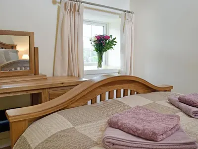 a bedroom with a bed and a mirror and a vase of flowers at Awel Y Mynydd - Mountain Breeze in Strata Florida