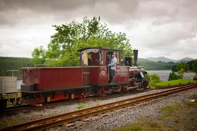 a man standing on a red train on the tracks at Sound of the River in Talgarth