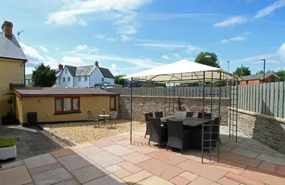 a patio with a table and an umbrella at Sound of the River in Talgarth