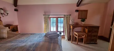 a bedroom with a bed and a desk and a window at Brynderwen Barn in Llangorse