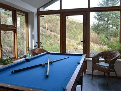 a blue pool table in a room with windows at Swallow Barn in Llanwrtyd Wells