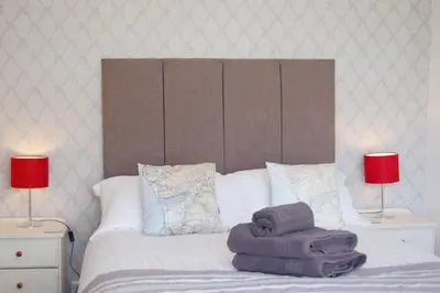a bed with two lamps and towels on it at Saint Cadfans Lodge in Tywyn