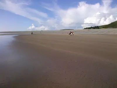 a group of people riding horses on a beach at Saint Cadfans Lodge in Tywyn