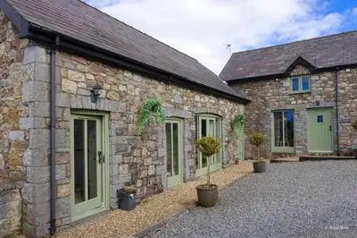 a row of stone buildings with green doors and potted plants at Rhiwddu Barns in Llangadog