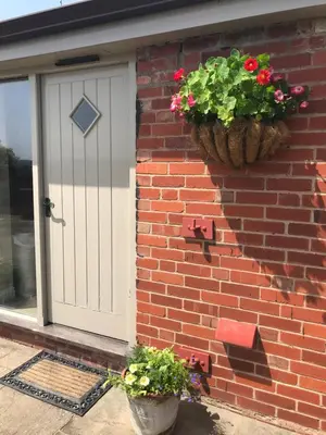 a brick house with a door and flower pots on it at Gaer Fawr Barns in Guilsfield