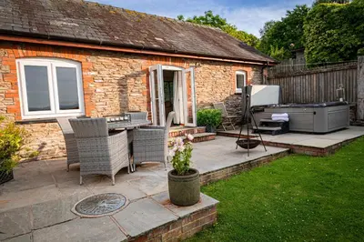 a patio with a table and chairs and a grill at Irfon Cottage in Builth Wells