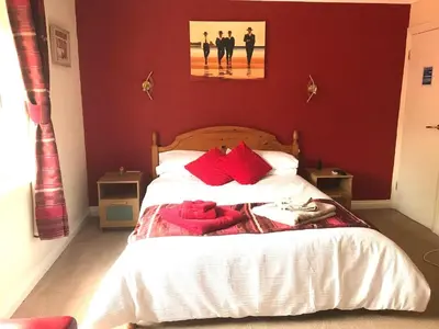 a bedroom with a large bed with red walls at Talybont B&B Aberystwyth in Talybont