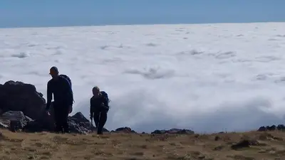 two people standing on top of a mountain with clouds at Dinas in Llanbedr