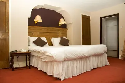 a bedroom with a large white bed with a wooden headboard at Gales Of Llangollen in Llangollen