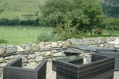 a stone wall with a picnic table and a stone bench at Dolffanog Fawr in Tal-y-llyn