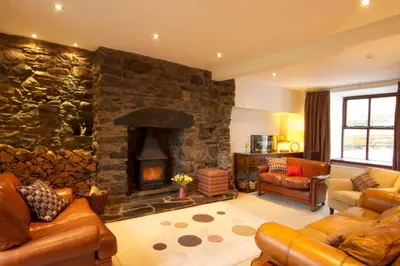 a living room with a stone wall with a fireplace at Dolffanog Fawr in Tal-y-llyn