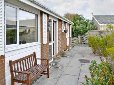 a wooden bench sitting outside of a house at Fairlawns in Fairbourne
