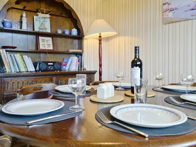 a wooden table with plates and a bottle of wine at Fairlawns in Fairbourne