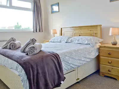 a bedroom with a bed and a dresser and a window at Fairlawns in Fairbourne