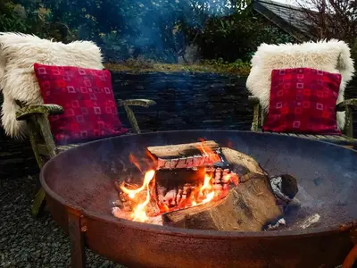 a fire pit with two chairs and a table with fires at Ty'n Y Ffordd in Llanymawddwy