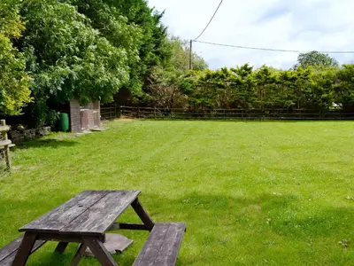a wooden picnic table in a grassy yard at Y Bwthyn in Bala