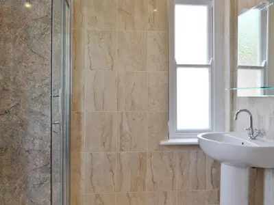 a bathroom with a sink and a glass shower at Cliff Railway Apartment in Aberystwyth