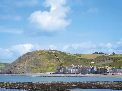a building on a hill next to the water at Cliff Railway Apartment in Aberystwyth