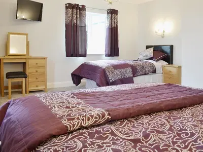 a bedroom with two beds and a desk and a window at Maes Rheidol in Capel Bangor