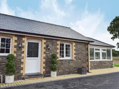 a stone cottage with a white door and windows at Maes Rheidol in Capel Bangor