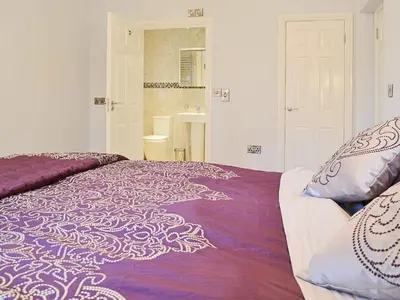 a bedroom with a bed with a purple and white blanket at Maes Rheidol in Capel Bangor