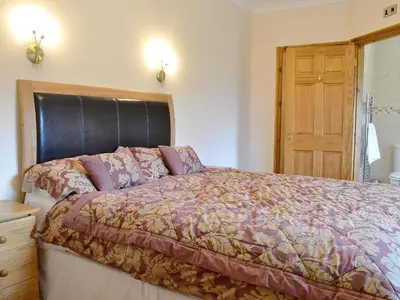 a bedroom with a large bed with a wooden headboard at 5 Pengraig Draw in Llanychaiarn