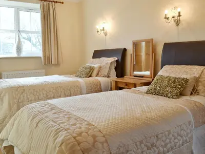 a bedroom with two beds and a window at 5 Pengraig Draw in Llanychaiarn
