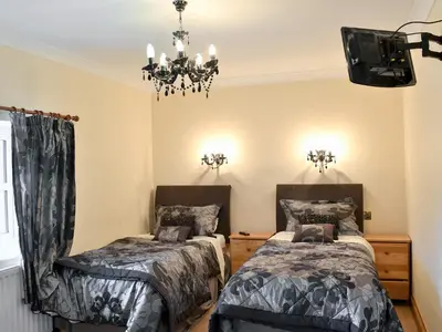 a bedroom with two beds and a chandelier at 4 Pengraig Draw in Llanychaiarn