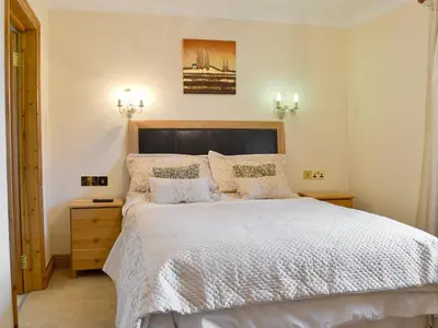 a bedroom with a large bed with white sheets and pillows at 4 Pengraig Draw in Llanychaiarn