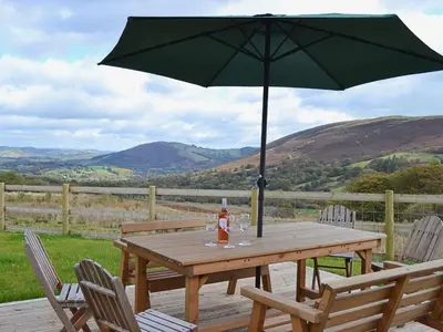 a wooden table with an umbrella on a deck at Gorsddu in Llanwrthwl