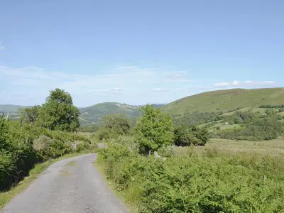a dirt road with trees and hills in the background at Gorsddu in Llanwrthwl
