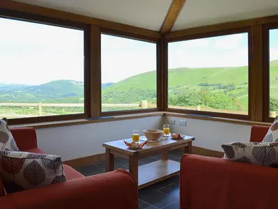 a room with two chairs and a table and windows at Gorsddu in Llanwrthwl
