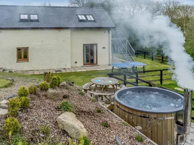 a house with a hot tub and a picnic table at Cwmhyfryd in Llanllwchaiarn